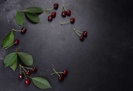 Fresh red cherries fruit on a plate on a dark concrete background. Close up