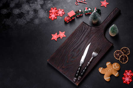 Christmas homemade gingerbread cookies, spices and cutting board on dark background with copy space...