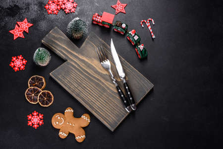 Christmas homemade gingerbread cookies, spices and cutting board on dark background with copy space...