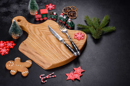Christmas homemade gingerbread cookies, spices and cutting board on dark background with copy space...