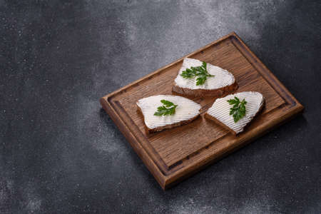Home made bread on a wooden cutting board with curd cheese and ricotta and herbsの写真素材