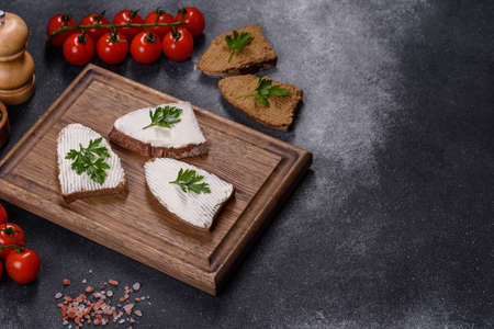 Home made bread on a wooden cutting board with curd cheese and ricotta and herbsの写真素材