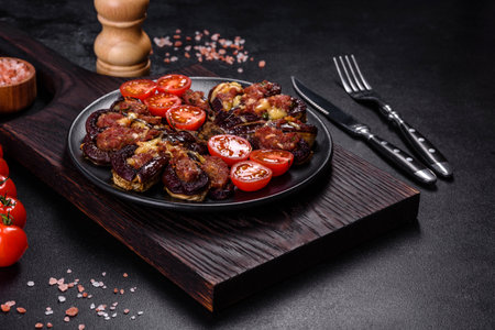 Fresh eggplant baked with minced meat, spices and herbs on a black plate against a dark concrete backgroundの写真素材