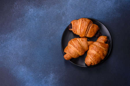 Crispy chocolate croissant with Christmas decorations on wooden cutting board on dark concrete backgroundの写真素材