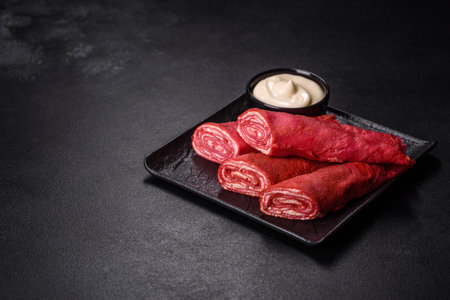 Delicious fresh red pancakes topped with beetroot juice with cheese and eggs on a dark concrete backgroundの写真素材