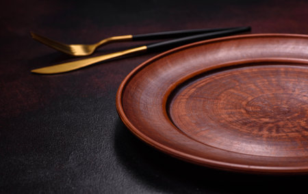 An empty brown ceramic plate on a dark concrete brown background. Preparing the Dinner Tableの写真素材