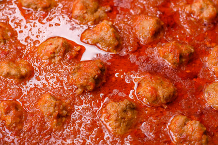 Delicious meatballs made from ground beef in a spicy tomato sauce served in a black panの写真素材