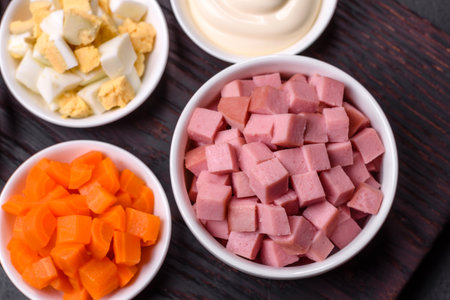 Delicious fresh Olivier salad with sausage, egg, cucumber, green peas, carrots and mayonnaise. hearty calorie foodの写真素材