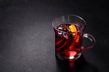 Christmas mulled red wine with spices and fruits on a concrete table. Traditional hot drink at...