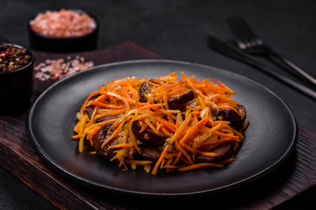 Korean salad with carrots and aubergine in a plate with garlic, black textured backgroundの写真素材
