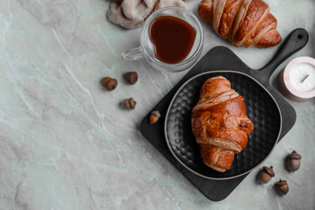 Delicious crispy croissant with chocolate with a cup of invigorating coffee on a light concrete background. Delicious nutritious breakfastの写真素材