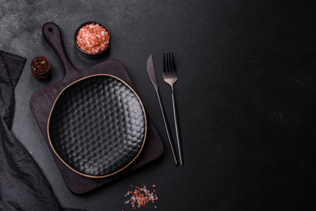 Black empty plate, cutlery and napkin on a stone table top view. Table settingsの写真素材
