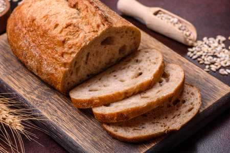 A loaf of brown bread with grains of cereals on a wooden cutting board on a dark concrete background
