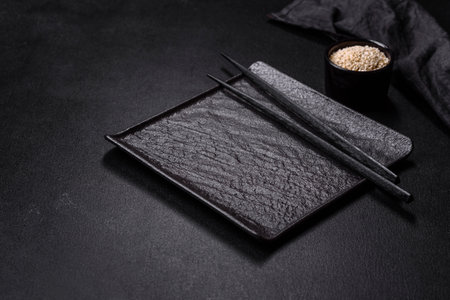 Empty plate with wooden sticks for Asian food on a dark concrete background. Asian cuisine preparationの写真素材