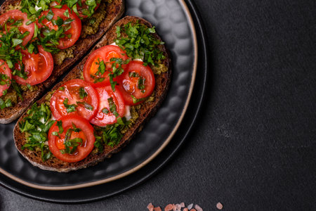 Tasty bruschetta with tomatoes, mozzarella, basil, spices and herbs on a dark concrete background