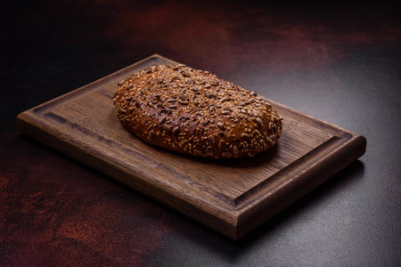 Delicious crispy bread with cereals on a wooden cutting board on a dark concrete background