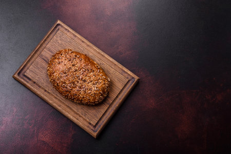 Delicious crispy bread with cereals on a wooden cutting board on a dark concrete backgroundの写真素材
