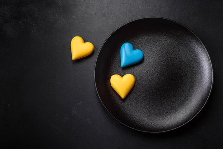 Chocolate hearts in the colors of the Ukrainian flag on a black ceramic plate. Valentine's day in Ukrainian colorsの写真素材