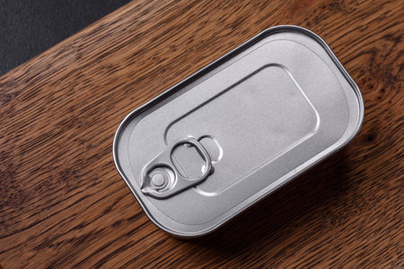 Tin or aluminum rectangular can of canned food with a key on a dark concrete backgroundの写真素材