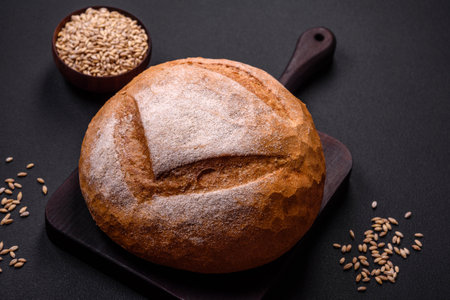 Beautiful delicious freshly baked round shaped white bread on a dark concrete backgroundの写真素材