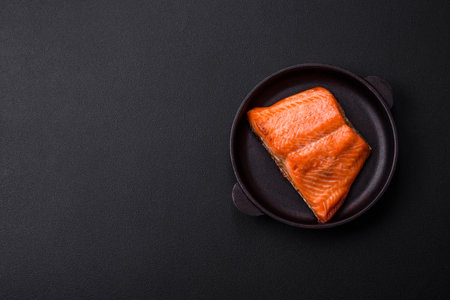 Delicious baked salmon red fish steak with spices and herbs on a dark concrete background