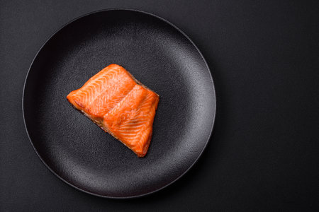 Delicious baked salmon red fish steak with spices and herbs on a dark concrete background