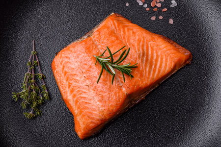 Delicious baked salmon red fish steak with spices and herbs on a dark concrete background