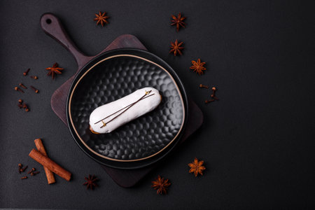 Delicious fresh profiterole or eclair with chocolate on a black ceramic plate on a dark concrete...