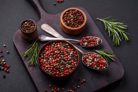 Spice allspice of different colors pink, white, green not ground in a wooden saucer on a dark...