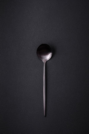 Empty metal spoon on dark textured concrete background. Cutlery, preparation for dinnerの写真素材