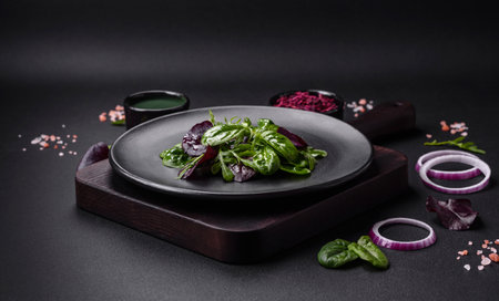 Delicious fresh salad consisting of spinach, chard, radicchio, red chart, bulls blood and arugula on a black plate on a dark concrete backgroundの写真素材