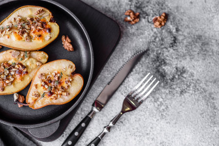 Delicious baked pear with dorblu cheese, walnut and honey on a textured concrete background. Vegetarian dishの写真素材