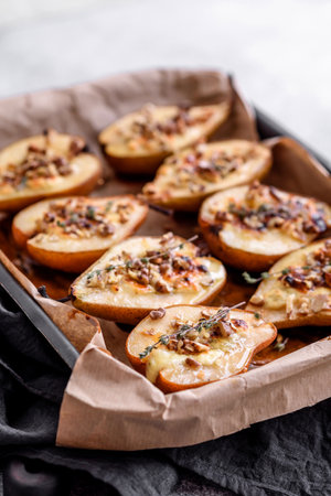 Delicious baked pear with dorblu cheese, walnut and honey on a textured concrete background. Vegetarian dishの写真素材