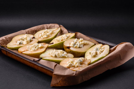 Delicious baked pear with dorblu cheese, walnut and honey on a textured concrete background. Vegetarian dishの写真素材