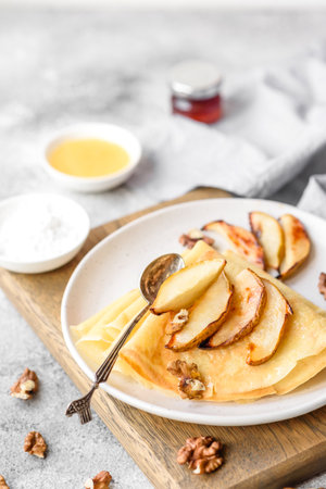 Delicious fresh baked pancakes with honey and fruits on a textured concrete background. Useful healthy foodの写真素材