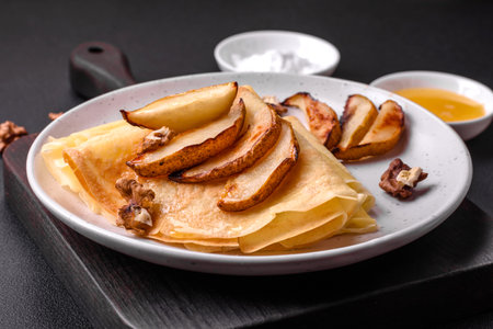 Delicious fresh baked pancakes with honey and fruits on a textured concrete background. Useful healthy foodの写真素材