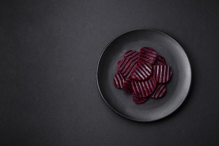Delicious healthy boiled ruby-colored beets sliced ??on a black plate on a dark concrete backgroundの写真素材