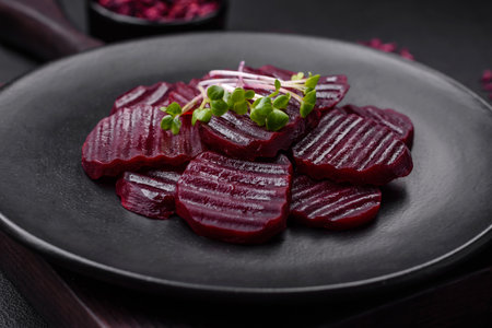 Delicious healthy boiled ruby-colored beets sliced ??on a black plate on a dark concrete backgroundの写真素材