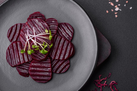 Delicious healthy boiled ruby-colored beets sliced ??on a black plate on a dark concrete backgroundの写真素材
