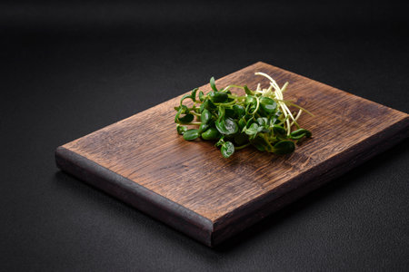 Fresh sprouts or sunflower microgreens on wooden cutting board on dark concrete backgroundの写真素材