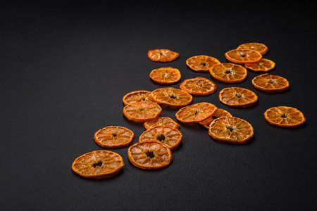 Dried round shape slices of bright orange color tangerine on a dark textural backgroundの写真素材