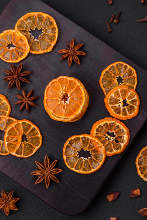 Dried round shape slices of bright orange color tangerine on a dark textural backgroundの写真素材