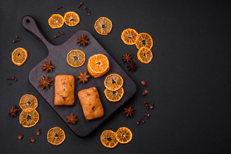 Delicious chocolate muffins and dried round shaped slices of bright orange color tangerine on a dark textural backgroundの写真素材