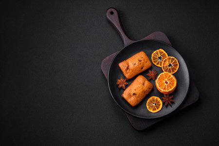 Delicious chocolate muffins and dried round shaped slices of bright orange color tangerine on a dark textural backgroundの写真素材