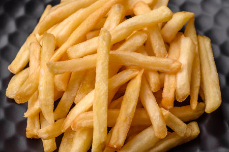Delicious crispy french fries with salt and spices on a dark concrete background. Unhealthy food, fast foodの写真素材