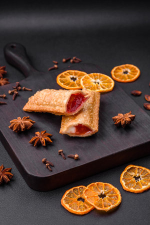 Delicious fresh crispy pie with cherry jam on a wooden cutting board on a dark concrete backgroundの写真素材