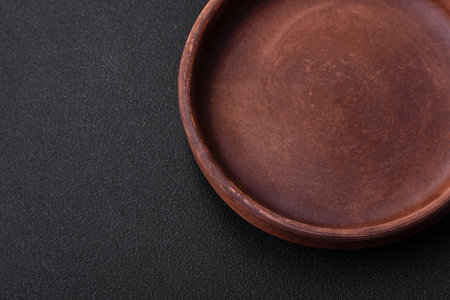 Empty brown colored ceramic plate on dark textured concrete background. kitchen utensilsの写真素材