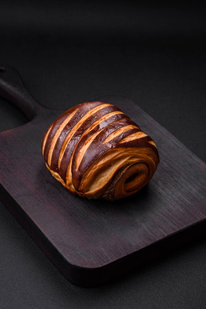 Delicious sweet crispy fresh baked cinnamon bun on dark concrete background