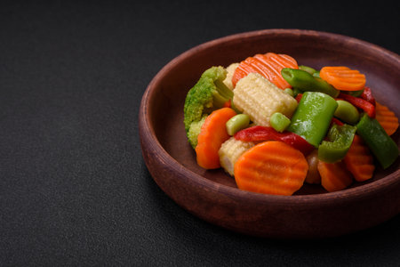 Delicious healthy vegetables steamed carrots, broccoli, asparagus beans and peppers on a dark concrete backgroundの写真素材