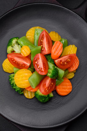 Salad of fresh and steamed vegetables cherry tomatoes, broccoli, carrots and asparagus beans on a dark concrete backgroundの写真素材